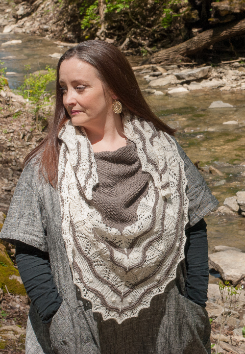 Mindy is looking to the side. She is wearing a brown and cream lace shawl.