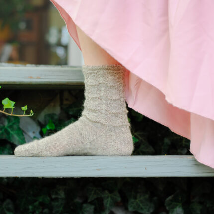a girl in a pink skirt wears a gray lacy sock
